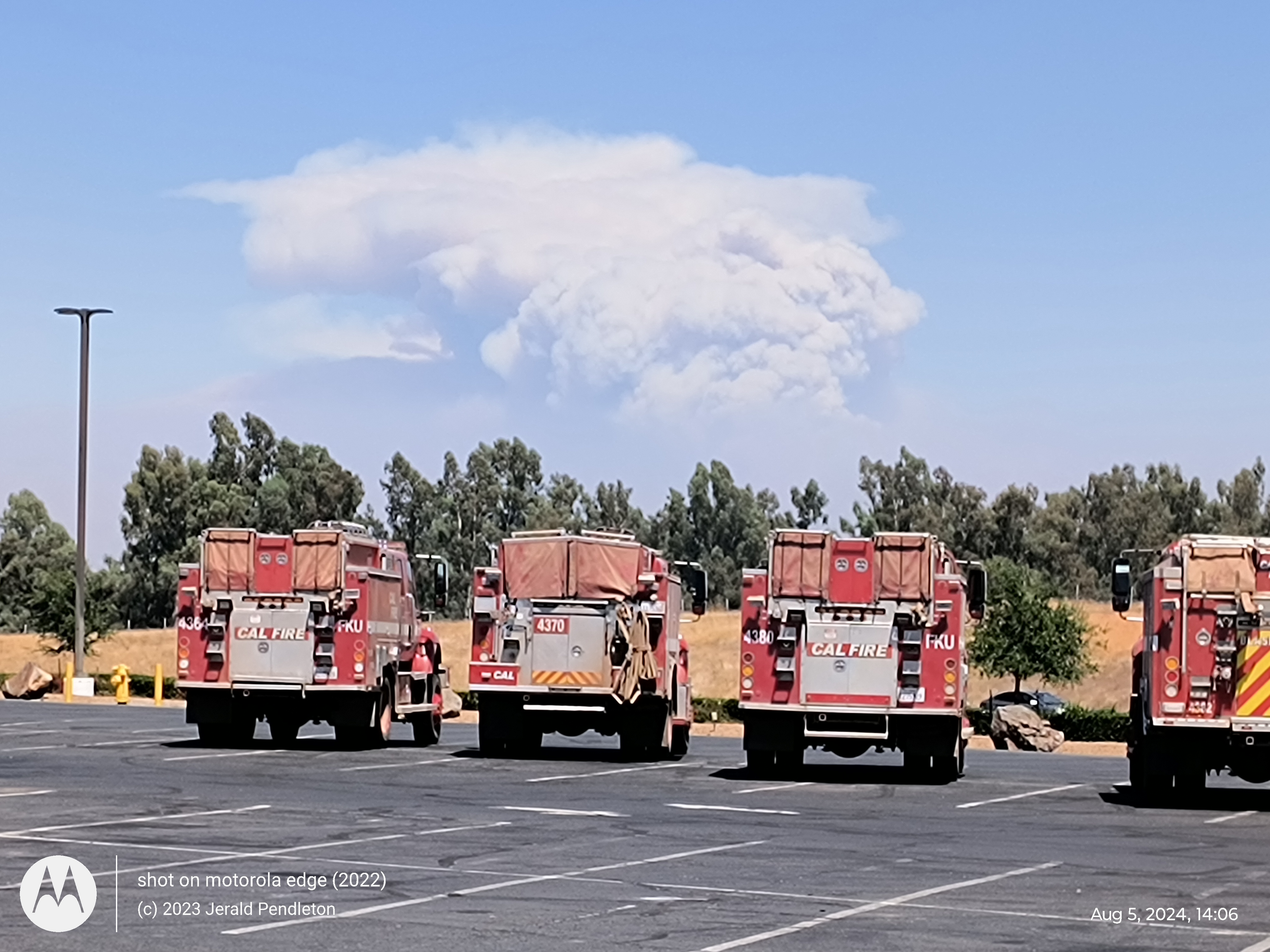 Fire trucks with smoke from the Park fire in the background